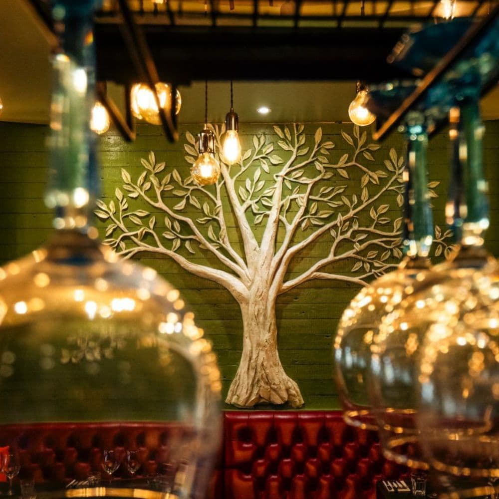 The olive tree sculpture at The Olive Tree, seen through warm glass pendant lights
